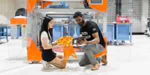 Two students inspect a 3D printed stool